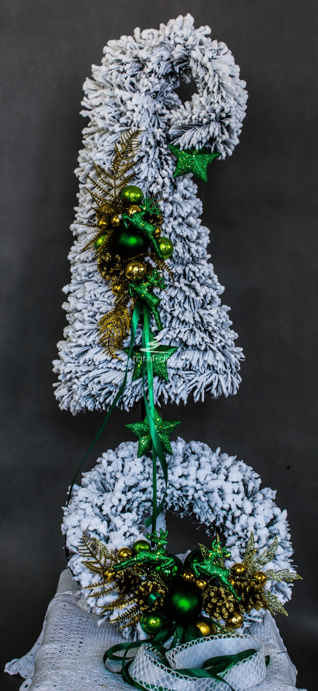 nowoczesny zestaw ośnieżonych dekoracji bożnarodzeniowych nowoczesne ozdoby świąteczne biała choinka na pniu zielone dodatki butelkowa zieleń wianek stroik oprószony śniegiem obielona