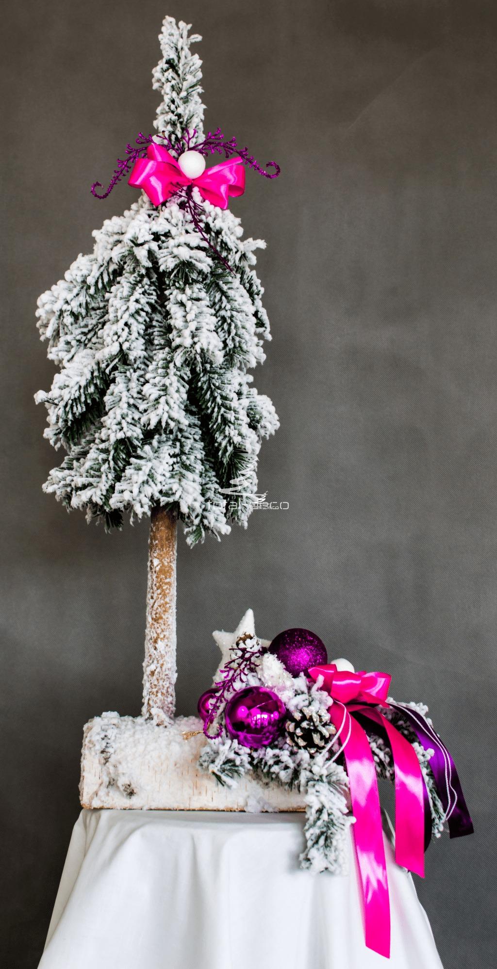 ośnieżona nowoczesna oryginalna choinka i stroik oprószona delikatnym śniegiem ubrana na różowo biało na drewnianej podstawie kokarda bombki dekoracja świąteczna ozdoba bożonarodzeniowa