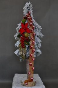 Choinka ośnieżona na biało ozdobiona dekoracjami złoto czerwonymi z mnustwem mikołajków świątecznych